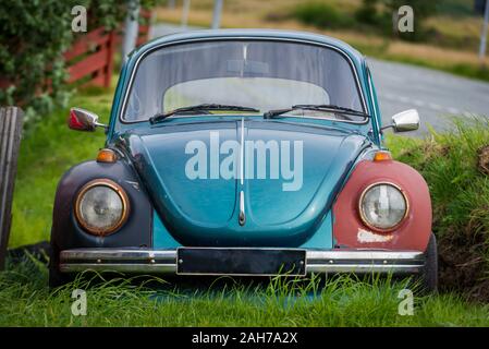 Vue de face d'une vieille voiture Volkswagen Beetle bleu clair et battue, située sur l'herbe dans un jardin en bord de route Banque D'Images