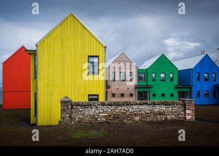 Une rangée de maisons en bois colorées dans le nord de l'Écosse sous un ciel nuageux Banque D'Images