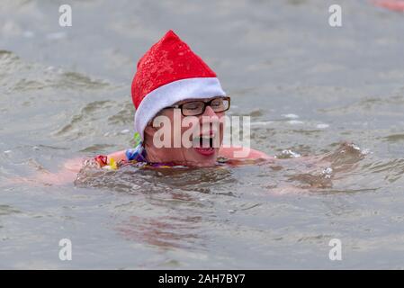 Plage du Jubilé, Marine Parade, Southend on Sea, Essex, Royaume-Uni. Comme c'est devenu une tradition dans la région de seaside endroits, un 'Boxing Day' Dip a eu lieu dans le froid, rugueux Thames Estuary à Southend collecter des fonds pour la RNLI. La plupart des nageurs portaient des habits de fête, courageux Banque D'Images