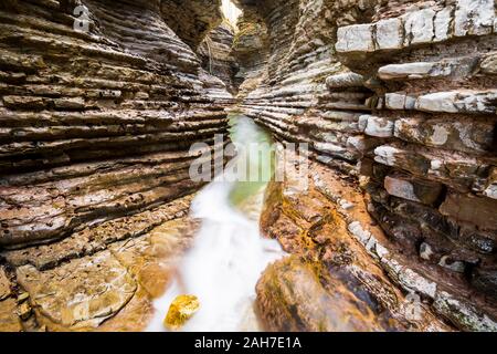 Vue symétrique grand angle d'un canyon en grès rouge stratifié avec un ruisseau qui s'étend sur son fond Banque D'Images