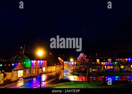 Les lumières de Noël reflètent dans les rues du village humide Bedfordshire village de Sharnbrook Banque D'Images