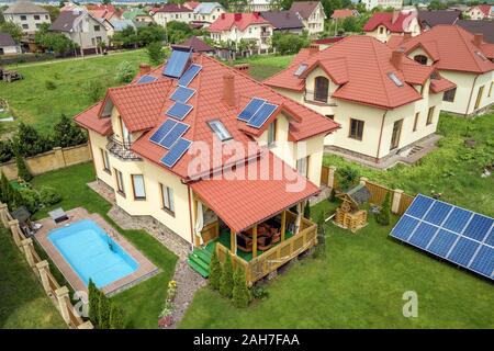 Vue aérienne d'une nouvelle maison autonome grâce à des panneaux solaires et les radiateurs de chauffage de l'eau sur le toit et jardin avec piscine bleu. Banque D'Images