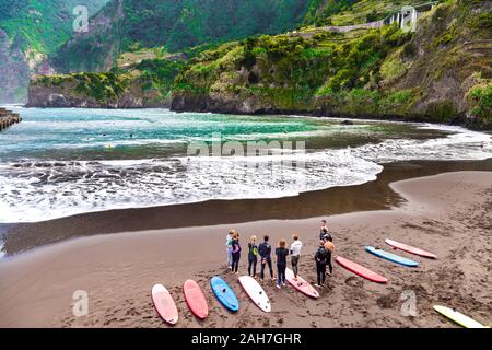 Un groupe de personnes avec des planches debout sur une plage de faire une classe de surf, Seixal, Madeira, Portugal Banque D'Images