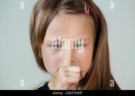 Close-up portrait of smiling little Girl with long hair à la croisée avec des yeux à son point de doigt. Banque D'Images