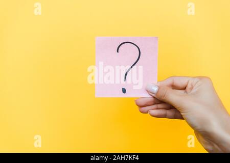 Portrait de femme tenant sticky note avec un point d'interrogation sur l'orange Banque D'Images