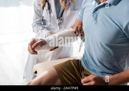 Portrait de l'orthopédiste mettre bandage sur la main blessée de l'homme Banque D'Images