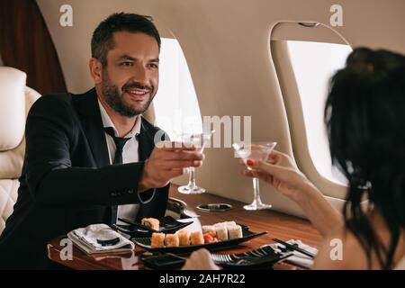 Portrait de femme tenant verres près de l'homme heureux en jet privé Banque D'Images