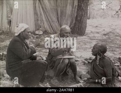 Au Kenya, deux hommes Kikuyu gesticuler à une ancienne femme Kikuyu assis sur le terrain qui, selon eux, a pris deux serments Mau Mau. Kenya, 1953.texte dactylographié de l'Original : Projection légende au Kenya : deux membres d'un Kikuyu de l'équipe de dépistage d'interroger une femme Kikuyu qui, selon eux, d'avoir pris deux serments Mau Mau. Elle refuse tout, 1953. 1995/076/7/8/3.27. Banque D'Images