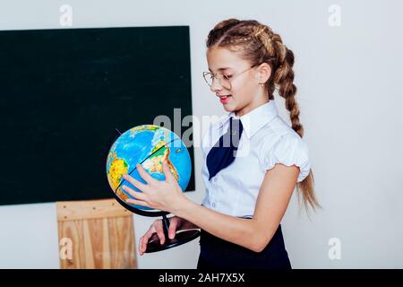 Fille avec un globe à la tableau noir dans une leçon de classe Banque D'Images