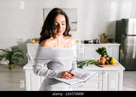 Jolie jeune fille tenant un ordinateur portable avec des lettres dans la cuisine Banque D'Images