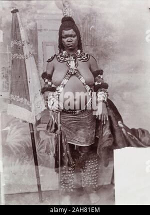 Le Nigeria, le marquage au verso : "Cette femme est une épouse choisie et dans la photo est devenue telle, et est vêtue de son costume de danse. Remarque le parasol sur la gauche. Elle est l'une de ces personnes qui, apparemment, sont mis dans un soi-disant 'college' pour être engraissé jusqu'ici, c'est et où elle vient de quitter et de devenir l'épouse. Certaines tribus comme leurs femmes graisse et quarante ! ! ! !. - Elle est belle n'est pas sucré ?', [c.1920s]. 2000/098/2/118. Banque D'Images