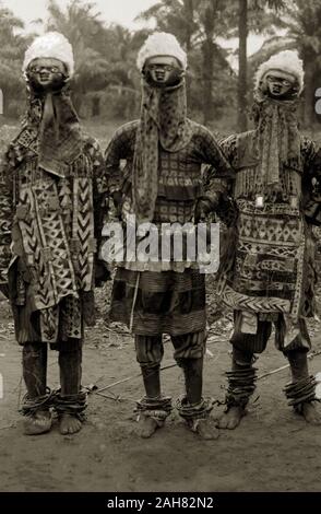 Le Nigeria, le marquage au verso : 'Juju les hommes dans leurs costumes'. Trois danseurs en costume juju porter des masques en bois sur le dessus de la tête, des vêtements à motifs et de cheville, [c.1920s]. 2/98/2000/098. Banque D'Images