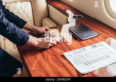 Portrait de l'agent de bord mettant tasse de café sur la table en avion privé Banque D'Images