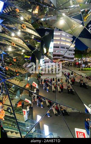 La salle des miroirs à l'entrée en bâtiment Tokyu Plaza Omotesando, Tokyo. Réflexions des escalators et rue avec passage pour piétons. La nuit. Banque D'Images