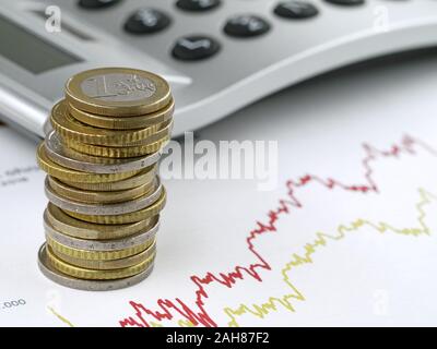 Les pièces en euros empilés sur calculatrice graphique avec trading sur le contexte, concept de croissance financière par le biais d'investir dans des actions Banque D'Images
