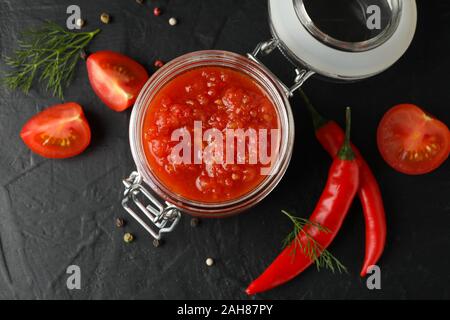 La sauce Chili dans un bocal en verre et d'ingrédients sur fond gris, de l'espace pour le texte. Vue d'en haut Banque D'Images