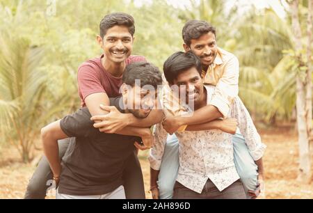 Meilleurs amis masculins Piggyback - Groupe d'amis s'amuser ensemble en plein air - Cheerful young male friends enjoying temps ensemble. Banque D'Images