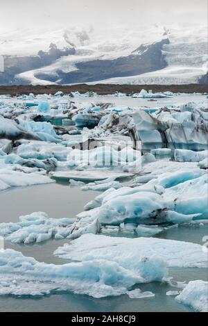 Vue emblématique sur le lagon islandais des icebergs, avec des icebergs en avant-plan et un glacier éloigné en arrière-plan Banque D'Images