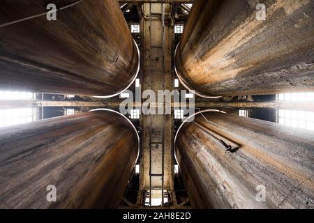 Vue symétrique à grand angle de quatre anciens silos industriels rouillés, tournés par le dessous Banque D'Images