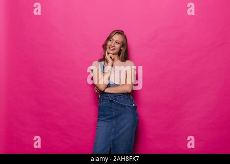 Belle jeune femme sérieuse et réfléchie de la pensée est isolé sur fond rose. Banque D'Images