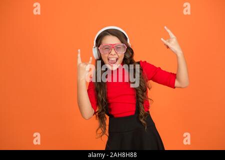 Cool la bonne voie. Liste de lecture pour partie. Music concept. Portez des lunettes pour enfants. Lunettes fashion store. Fille avec lunettes sur fond orange. Et d'événements de divertissement. Party Girl. Partie accessoire. Avoir du plaisir. Banque D'Images