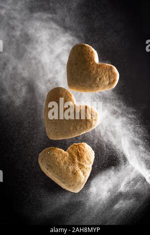 Les cookies en forme de coeur léviter en vol en nuage de farine Banque D'Images