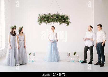 Belle femme en blanc maître cérémonie robe bleu permanent, sous l'arch pin avec demoiselles et groommen avant la cérémonie de mariage. W Banque D'Images