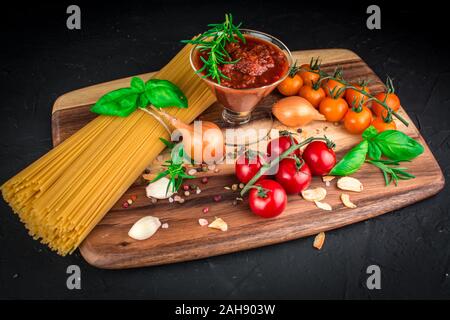 Ensemble d'ingrédients pour les pâtes à la bolognaise végétarienne . Arrière-plan de l'alimentation noir . Les pâtes, les tomates, le basilic, l'ail, l'oignon, les herbes assaisonnement , Banque D'Images