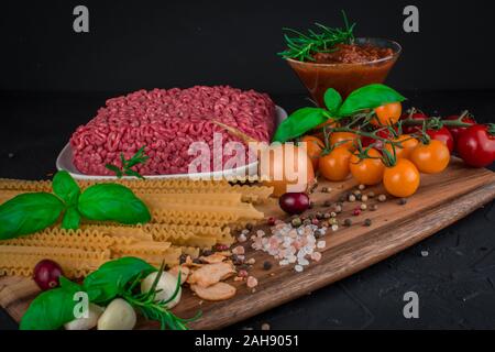 Ensemble d'ingrédients pour les pâtes à la bolognaise . Arrière-plan de l'alimentation noir . Les pâtes, hacher les tomates,l'ail, basilic, fines herbes, oignon , assaisonnement , Banque D'Images