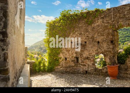 Une cour intérieure avec vue sur les montagnes de la Ligurie et l'ancien mur couvert de lierre en haut de la Dolceacqua Château en Italie Banque D'Images