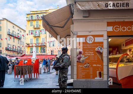 Un jeune homme noir d'agent de sécurité de l'armée française avec un béret et carabine automatique monte la garde à l'intérieur de centre-ville de Nice, France. Banque D'Images