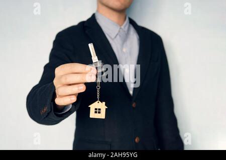 Holding clés de maison sur trousseau en forme de maison concept pour l'achat d'une nouvelle maison. guy dans l'action me montre les touches. La chaîne de clé sous la forme d'une maison dans un ma Banque D'Images