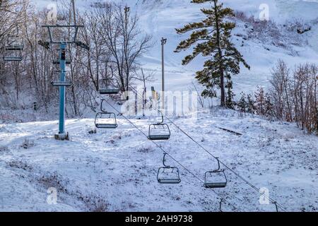 Un télésiège est visible sur le côté d'un centre de ski, ses sièges vides suspendus et immobile que la colline est préparé pour les skieurs et snowboarders prêt à aller. Banque D'Images