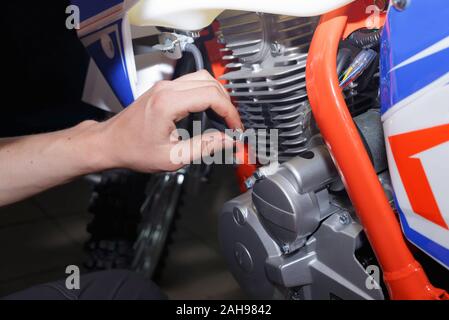 Motocycliste, remplace la bougie de chèques dans une moto. Remplacement de l'étincelle dans l'atelier de réparation. Banque D'Images