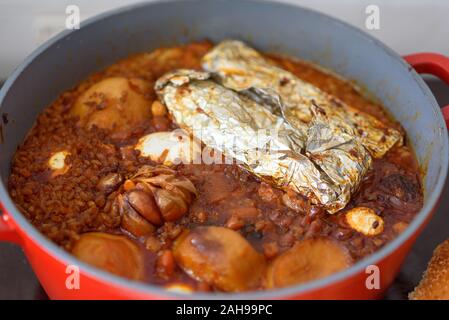 La plaque chaude pour le Sabbat, un pot de viande épicé cuit avec des pommes de terre, orge, jachnun,l'ail,le blé et les œufs. Pot de tcholent Hamin en hébreu, en vue d'en haut. La nourriture traditionnelle Shabbat juif. Banque D'Images