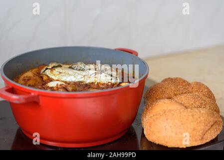 La plaque chaude pour le Sabbat, un pot de viande épicé cuit avec pommes de terre, blé, orge et d'œufs. Pot de tcholent Hamin en hébreu, challah-pain spécial dans une cuisine juive. La nourriture traditionnelle Shabbat juif. Banque D'Images