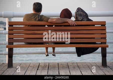 Une famille musulmane iranienne profite d'un Seaview sur une terrasse près d'un parc. Père, mère et filles ont fait un cercle intime comme temps de famille. Banque D'Images