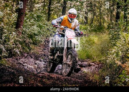 Enduro motocross racer équitation sur piste forestière humides et boueuses Banque D'Images