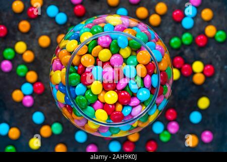 Bonbons bonbons colorés dans un pot sur fond sombre - vue d'en haut. Banque D'Images