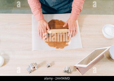 Vue de dessus d'une jeune femme brune pétrissez une pâte pour faire des cookies à la maison pendant les vacances de Noël. Handmade christmas Banque D'Images