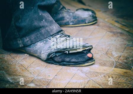 Vieilles bottes déchirées sur les pieds de l'homme. Bottes avec des trous. Selective focus Banque D'Images