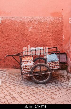 Transporteur avec des œufs contre un mur rouge dans le centre de Medina. Marrakech, Maroc. Banque D'Images