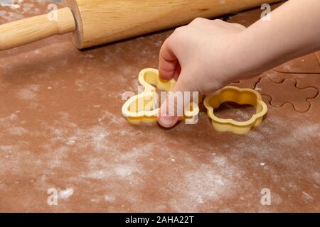 Les figures de coupe dans la pâte à l'aide des pochoirs pour faire des biscuits de Noël au gingembre. Les mains des enfants de près. Famille d'accueil, se préparer à la Banque D'Images