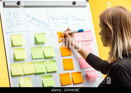 Businesswoman standing près de white flipchart, écrit sur les notes d'autocollants Banque D'Images