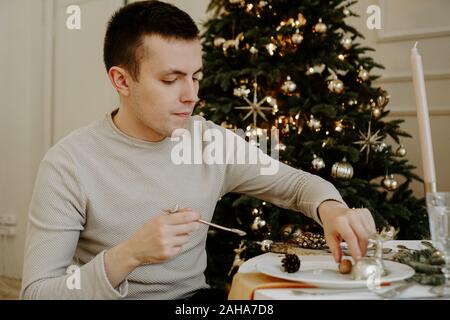 L'homme à la table de noël. Arbre de Noël sur fond intérieur lumineux d'or Banque D'Images