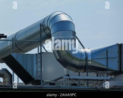 Grand circulaire en tôle d'acier galvanisé brillant du conduit d'air mécanique sur toit plat. L'unité de condensation. génie du bâtiment système de refroidissement du bâtiment. Banque D'Images