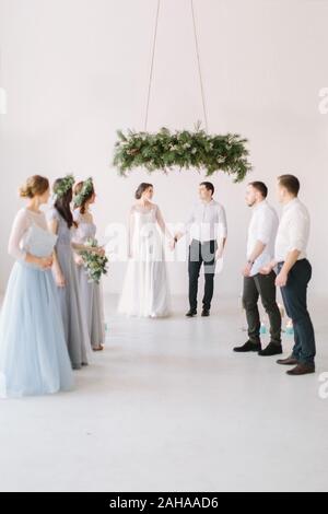 Les jeunes mariés profiter de moment romantique ensemble lors de la cérémonie du mariage, les invités du mariage en arrière-plan de jeter du riz. Banque D'Images