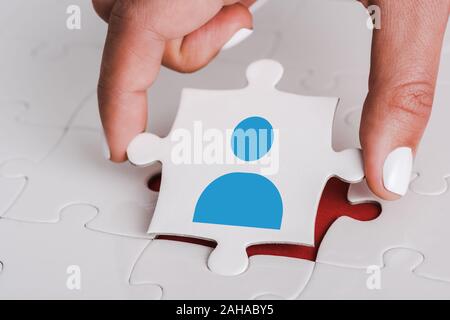 Close up of woman holding white jigsaw avec l'icône de l'bleu près de connecté des pièces de puzzle Banque D'Images