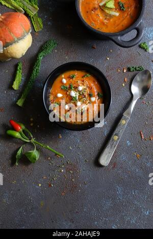 Vue de dessus de soupe au potiron avec de la crème d'épices sur fond sombre. Banque D'Images