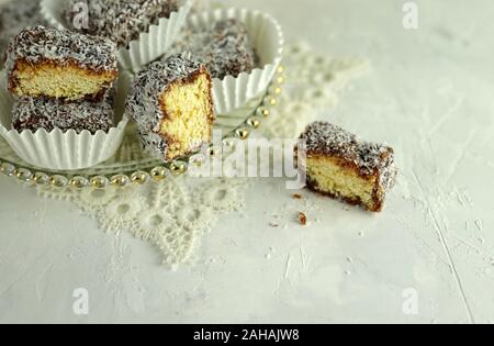 Gâteau traditionnels australiens. Lamington Australie gâteau au chocolat et noix de coco sur fond blanc. Banque D'Images